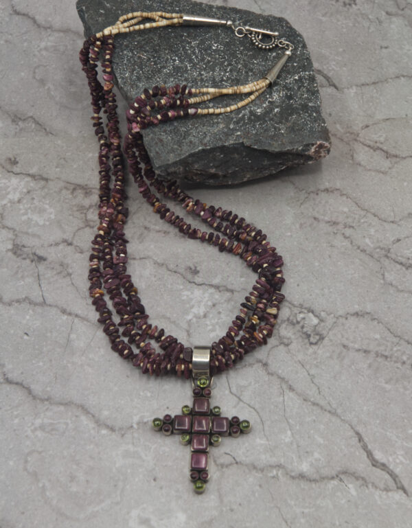 A cross necklace is sitting on the ground.