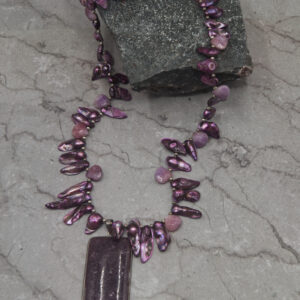 A purple necklace with a rectangular pendant on it.