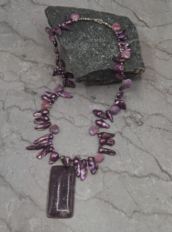 A purple necklace with a rectangular pendant on it.