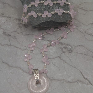 A necklace with a pink bead and a silver chain.