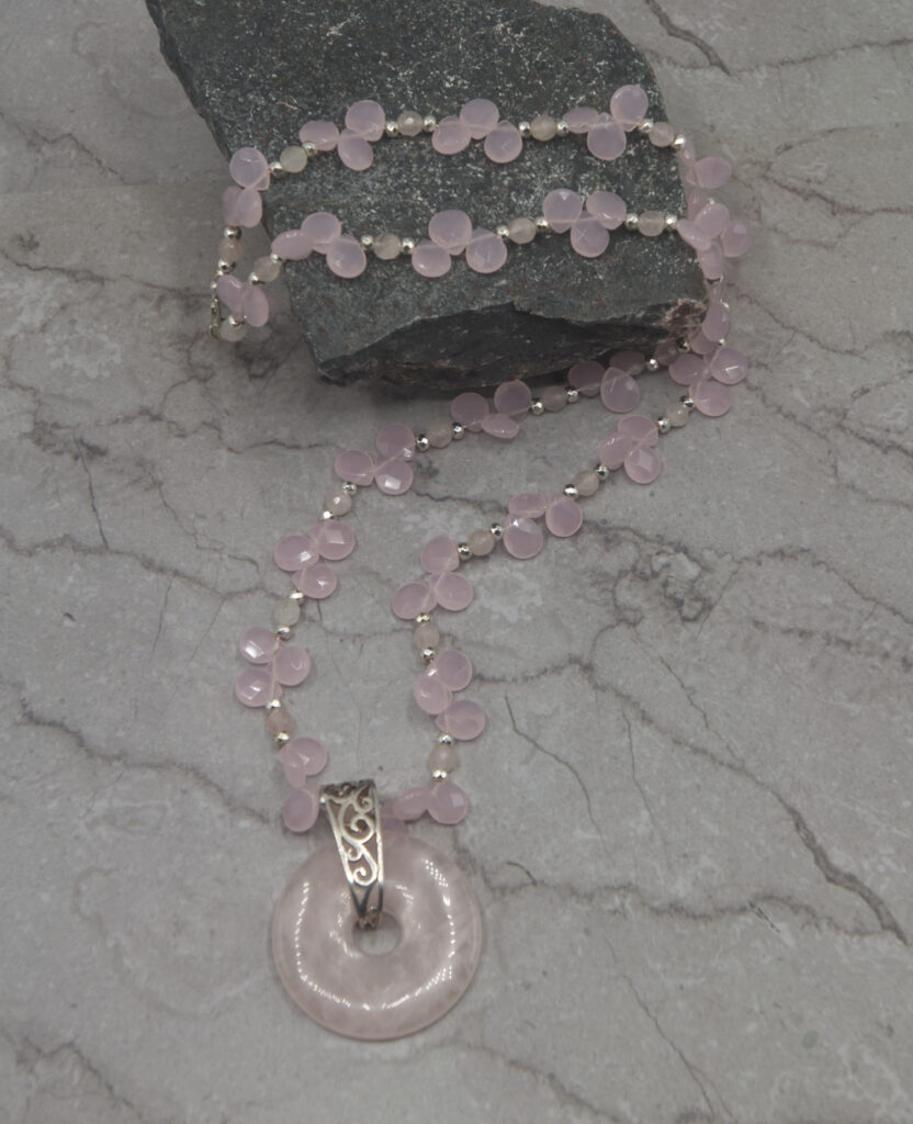 A necklace with a pink bead and a silver chain.