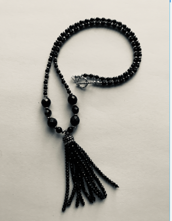 A black bead necklace with a tassel on it.