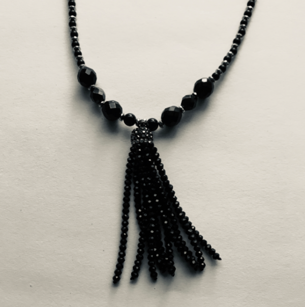 A black beaded necklace with a tassel hanging from it.