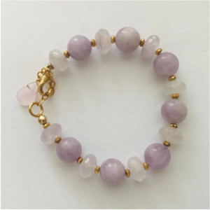 A bracelet with purple and white beads on it.