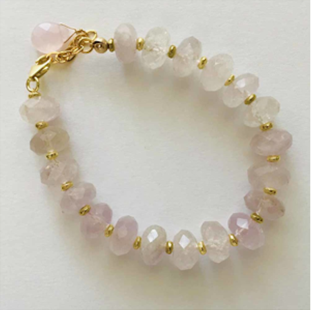 A bracelet with pink beads and gold accents.